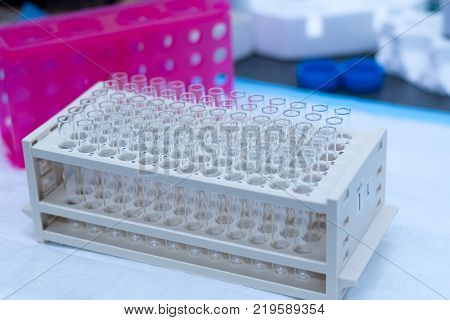 Chromatography fraction collector tubes on a rack holding 72 empty glass tubes on a lab bench as viewed from the right.