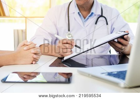 Scientist In White Coat Holding And Examining Test Tube With Reagent Making Notes Of His Research In