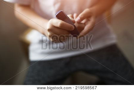 The doctor takes the blood from the boy with a finger using a scarifier. They make the procedure on the table in the medical office.