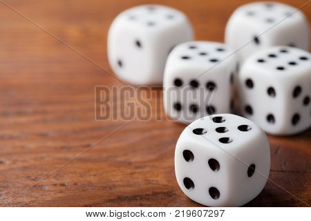 Dice on rustic wooden table. Gambling devices. Game of chance concept. Macro shot.