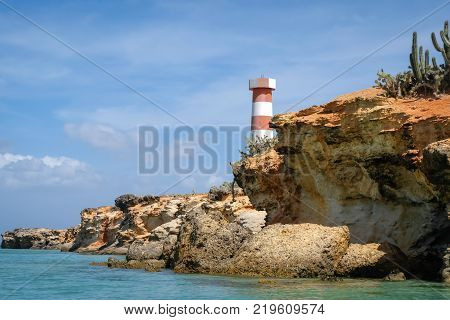 Travel photography - coast seascape with a light house and tropical vegetation (Cubagua island, Venezuela).