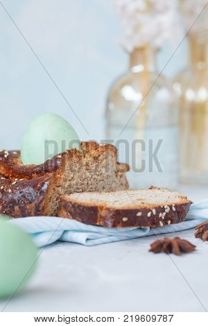 Traditional Greek Easter bread - tsoureki sliced in Easter decoration with painted eggs and flowers. Easter Festival concept.