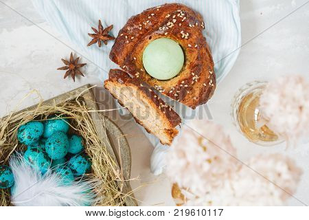 Traditional Greek Easter bread - tsoureki sliced in Easter decorations with painted blue quail eggs in the nest and flowers. Easter Festival concept.