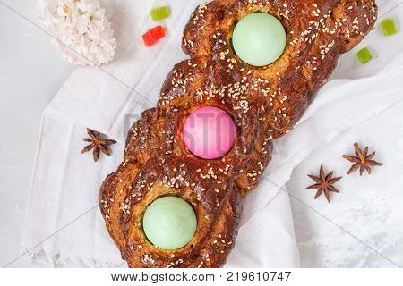 Traditional Greek Easter bread - tsoureki in Easter decorations with painted eggs and flowers. Easter Festival concept.