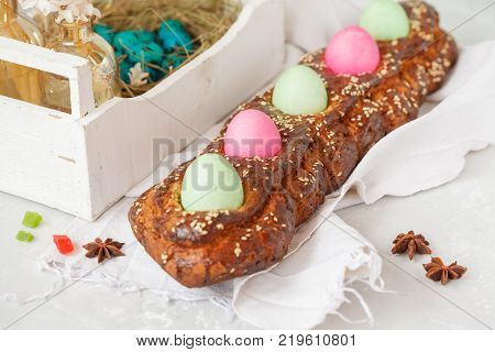 Traditional Greek Easter bread - tsoureki in Easter decorations with painted eggs and flowers. Easter Festival concept.