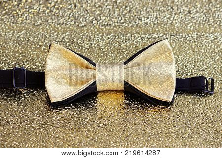 A festive golden with a black bow tie on a gold background