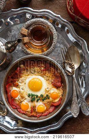 Turkish cured beef and fried eggs in copper pan, traditional breakfast, top view.