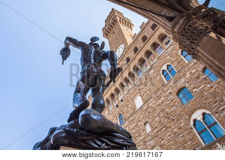 Perseus with the Head of Medusa under Loggia dei Lanzi against Palazzo Vecchio Florence Italy