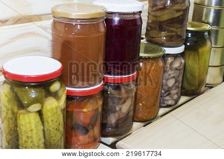 Storage shelves in pantry with homemade canned preserved fruits and vegetables.
