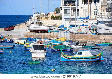 SAN PAWL, MALTA - APRIL 2, 2017 - Traditional Maltese Dghajsa fishing boats moored in the harbour with town buildings to the rear San Pawl Malta Europe, April 2, 2017.