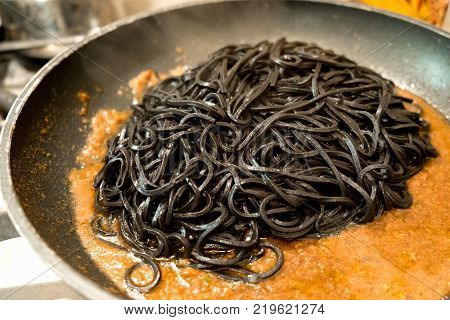 black pasta squid ink in a pan - italian taglierini al nero di seppia recipe.