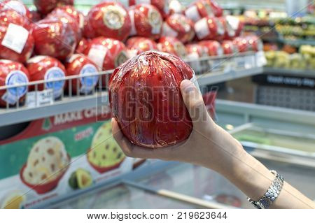 A woman is holding a edam cheese at the marker