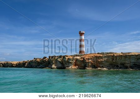 Travel photography - seascape with a light house and rocks sailing along the coast of Cubagua island (Venezuela).