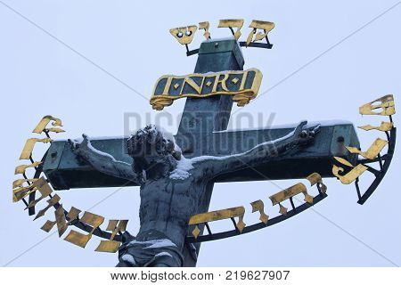Jesus on cross on Charles Bridge in winter morning during snawfall, Pague, Czech Republic