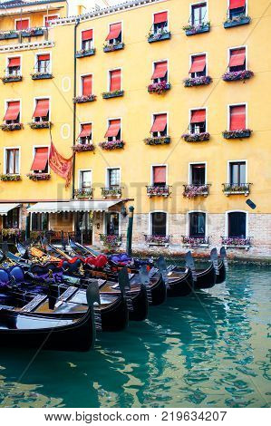 Row of gandole near colorful house in Venice, Italy.
