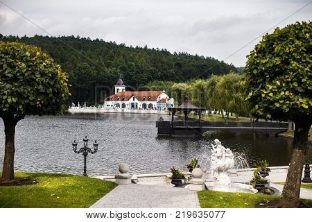 House and stone foutain in a forest on a lake.