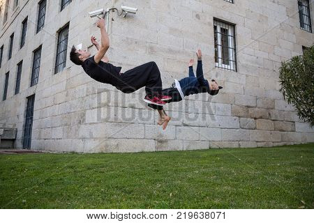 Two young men doing a side flip or somersault while they practicing parkour on the street.