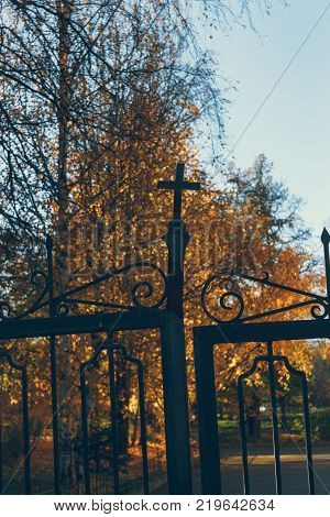 old church gate with a cross against the background of autumn leaves and the blue sky