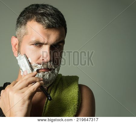 Serious hipster in barbershop new technology. Haircut of bearded man archaism. Barber and hairdresser. Fashion and beauty innovation. Man cut beard and mustache with razor and shaving brush.