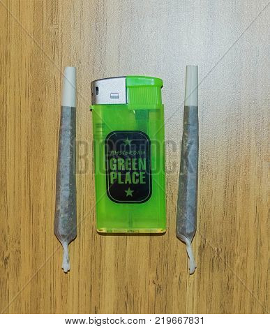 Amsterdam, Netherlands - December 14, 2017: The lighter and Pre-rolled marijuana joint on wooden background at Amsterdam, Netherlands on December 14, 2017