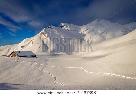 Early morning sun breaking through over a fantastic mountain landscape covered with a lot fresh snow. On the left of the picture the 