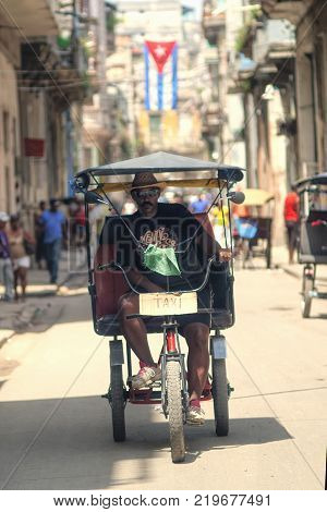 Havana, Cuba - July 2014: A man riding a  pedicap a sunny day at Havana streets