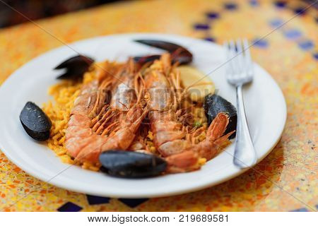 Royal Paella. Tasty Rice with king prawns and mussels  on white plate with fork