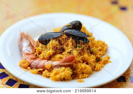 Royal Paella. Tasty Rice with king prawns, mussels and lemon on white plate