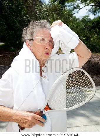 Aktivní senior žena vezme přestávku od squash na sebe ručník z.