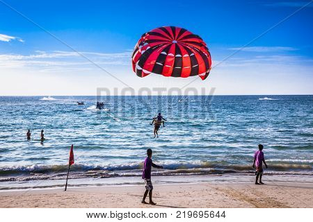 PHUKET, THAILAND - JAN 23, 2016: Tourists playing parasailing on Patong beach in Phuket on Jan 23, 2016, Thailand. Patong is a beach resort town on the west coast of Phuket Island.