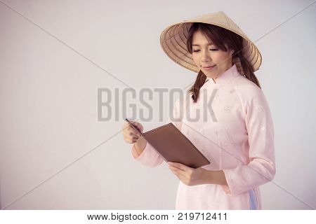 beautiful woman in pink dress and vietnam hat holding book