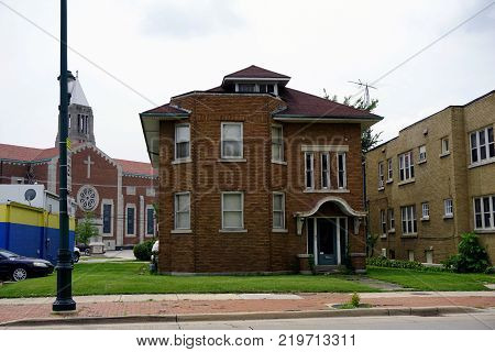 JOLIET, ILLINOIS / UNITED STATES - JULY 26, 2017: A brown brick two-story apartment building, in front the of Cathedral of Saint Raymond Nonnatus, on Plainfield Road in Joliet.