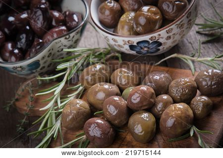 Cured, pickled or brined olive fruit on wooden table