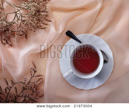 China Teetasse auf Rosa Stoff mit getrockneten Blumen von oben gesehen