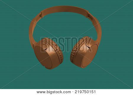 Golden wireless headphones on green background. Flat style. Design and colors