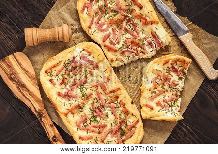 Tarte flambee, traditional alsatian pizza on wooden background.