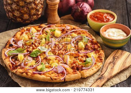 Homemade hawaiian pizza on black wooden background.
