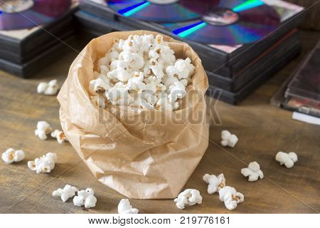 Pop corn and laser discs on a wooden surface. Rustic style, selective focus.