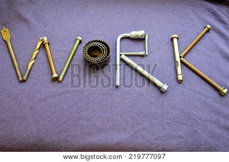 The inscription work is written by metal anchor bolts screws svermami wrenches. Work made up of objects. The word work is made up of a metalwork tool on a purple background.