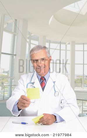Usmívající se středním věku lékař v laboratorní plášť podal předpis směrem k fotoaparátu. Člověk sedí v