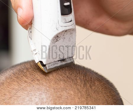 Man having a haircut with a hair clippers .