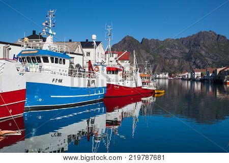 Henningsvaer Norway - August 19 2017: Picturesque fishing port in Henningsvaer on Lofoten islands Norway with typical red wooden buildings and small fishing boats