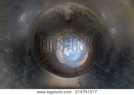 inside tube or pipe of great metal slide in playground with light at the end of tunnel or hole