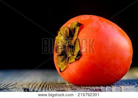 Fresh ripe juicy persimmon with water drops on wooden table. Rustic harvest concept. Selective focus