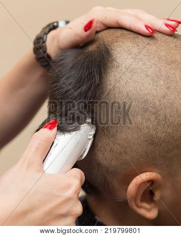 Man having a haircut with a hair clippers .