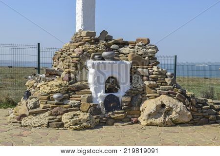 Outdoors whitewashed stove high chimney, lined with pebbles and shell stone. Decorated stone Russian stove for cooking food on the street.