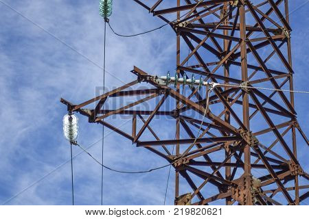Supports high-voltage power lines against the blue sky with clouds. Electrical industry.