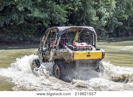 The man on the ATV crosses a stream. Tourist walks on a cross-country terrain.