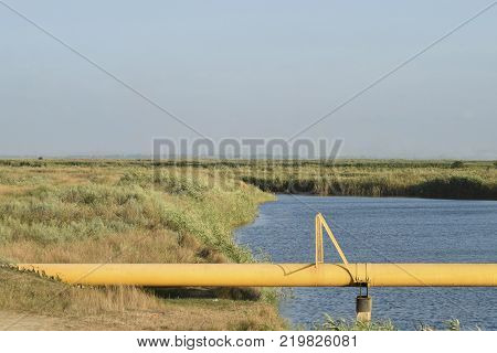 The gas pipeline through the small river. Equipment of oil and gas crafts.
