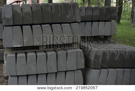 Stack of concrete curbstone. Construction process the dark one